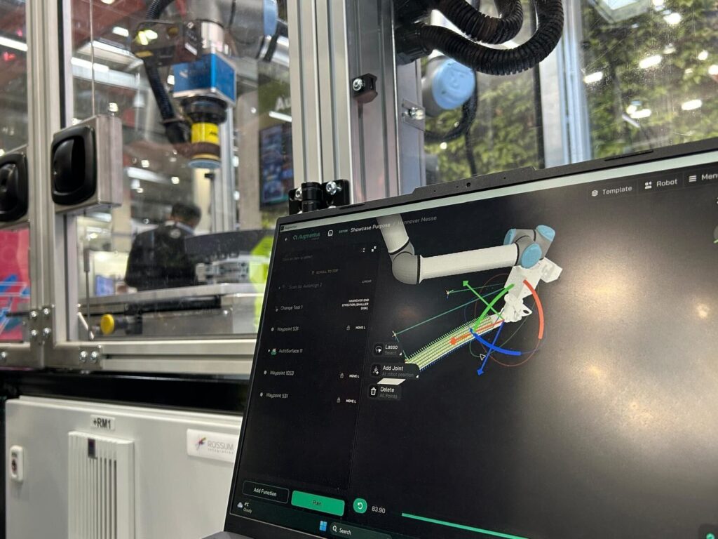 An engineer supervises a robot cell as it runs a sanding toolpath entirely programmed in Augmentus.